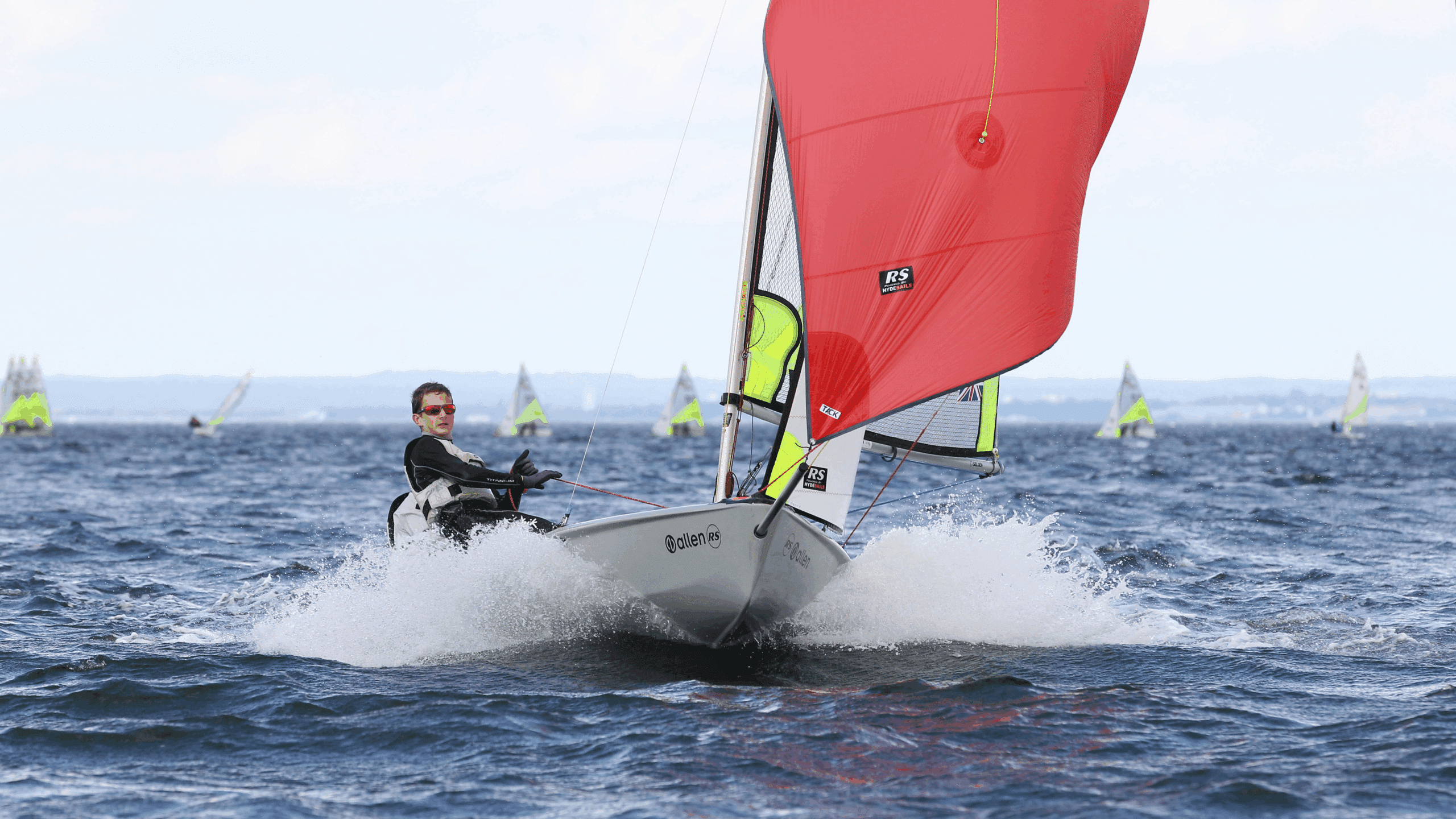 Person segelt im Meer mit rotem Segel
