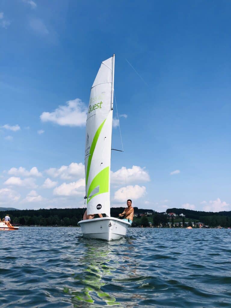Mann segelt auf kleinem Boot im See.